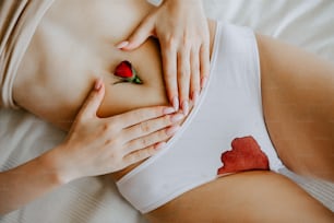 a woman laying on a bed with a rose on her stomach