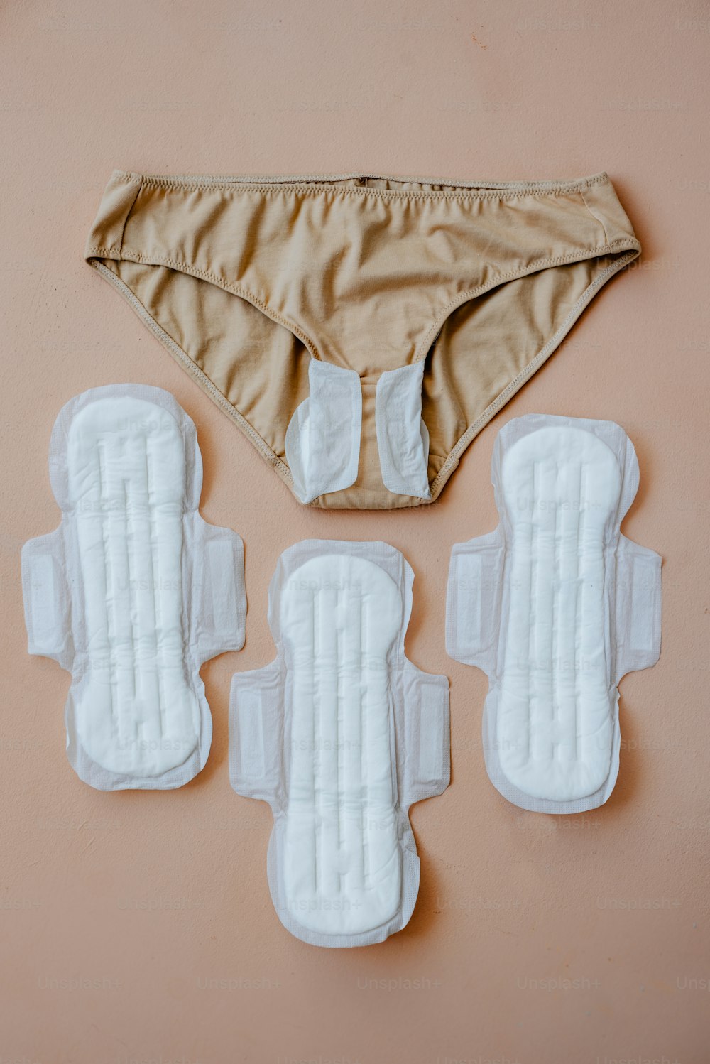 A pair of underwear and underwear pads on a pink surface photo