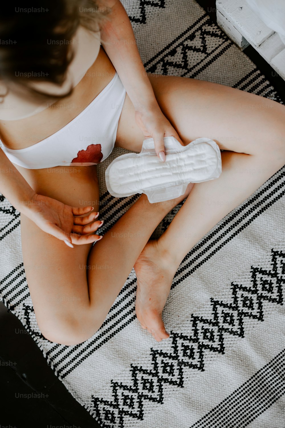 Eine Frau im weißen Bikini sitzt auf einem Bett