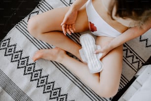una donna seduta su un letto con in mano un asciugamano santiario
