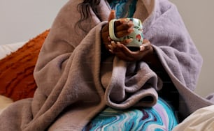 a woman wrapped in a blanket holding a cup