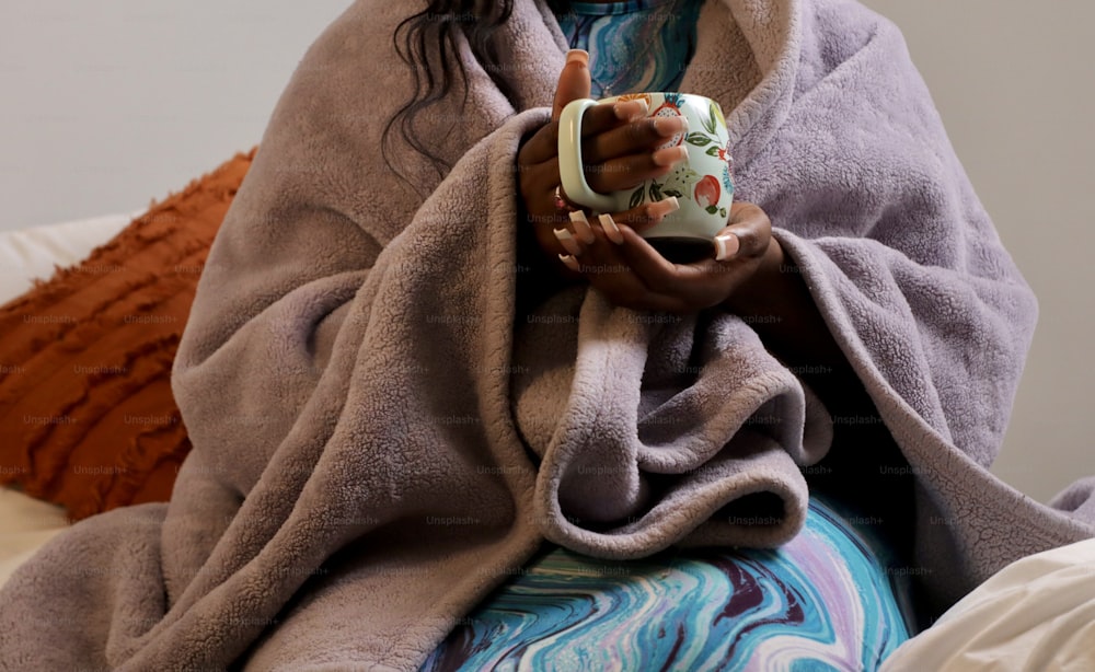Eine Frau, die in eine Decke gehüllt ist und eine Tasse hält