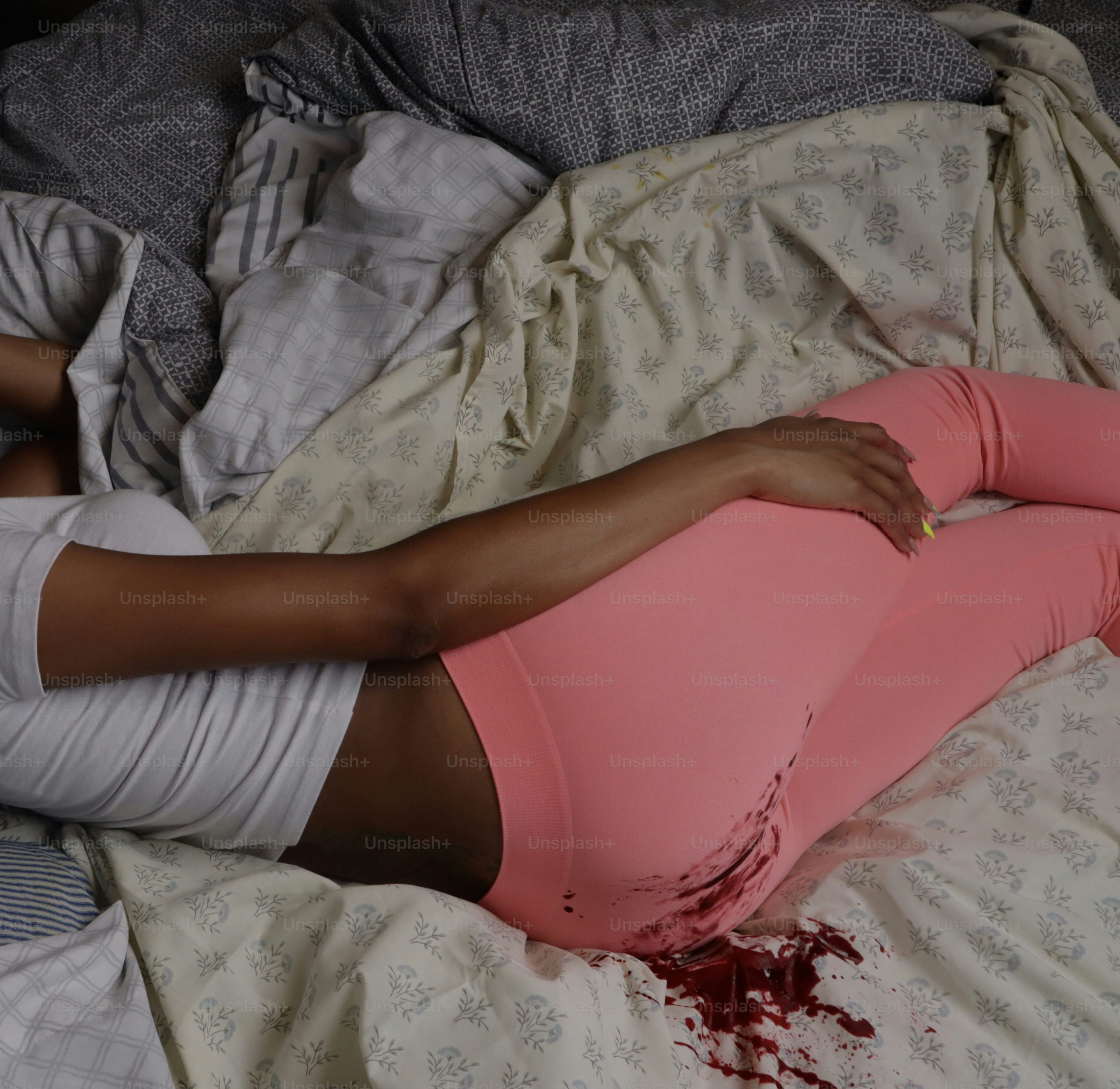 Una mujer acostada encima de una cama cubierta de sangre