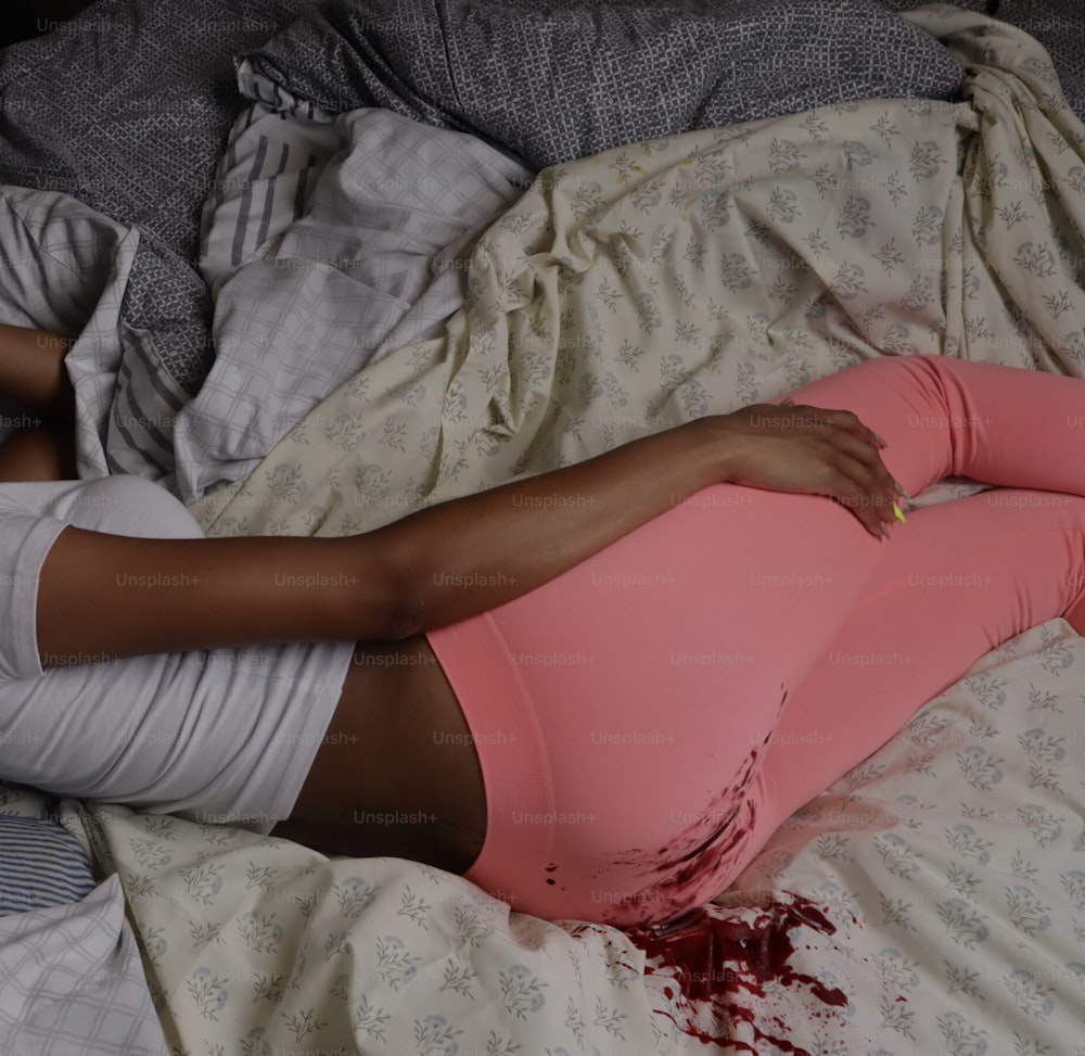 a woman laying on top of a bed covered in blood