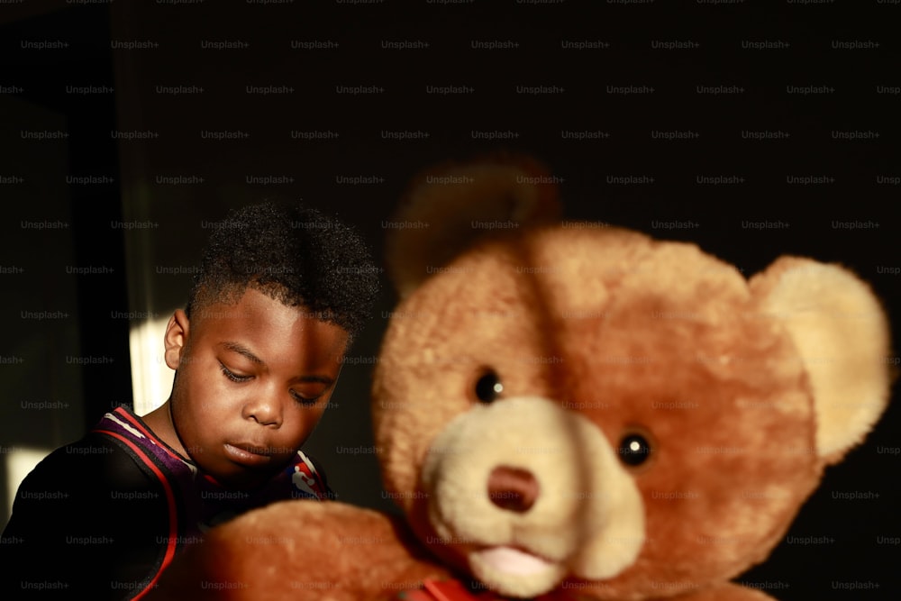 a young boy is looking at a teddy bear