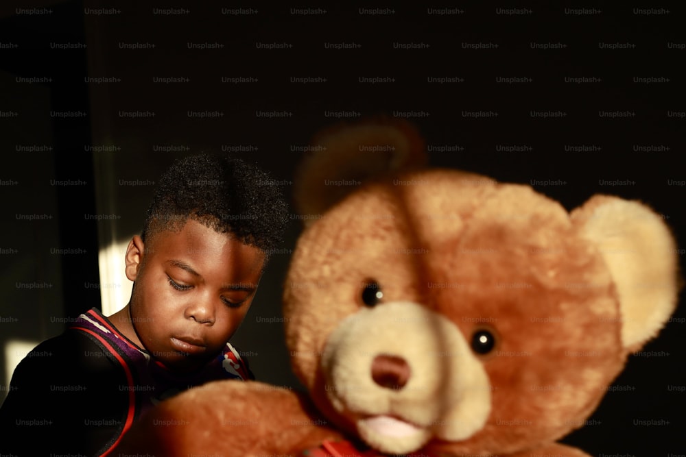 Ein kleiner Junge schaut auf einen Teddybären