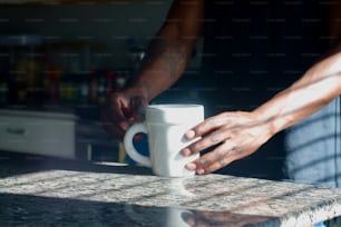 eine Person, die eine Kaffeetasse auf einer Theke hält