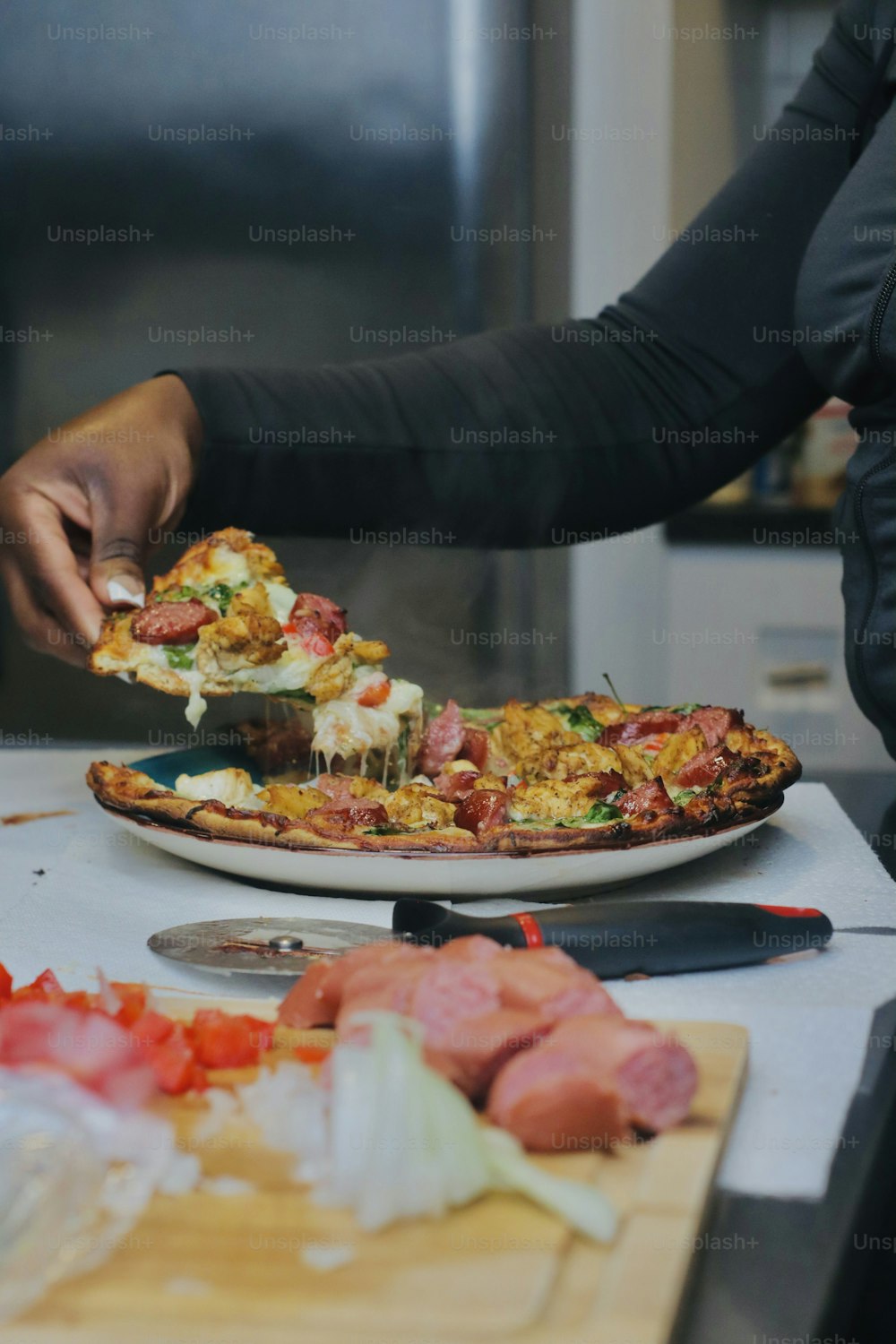 a person cutting a pizza on a cutting board