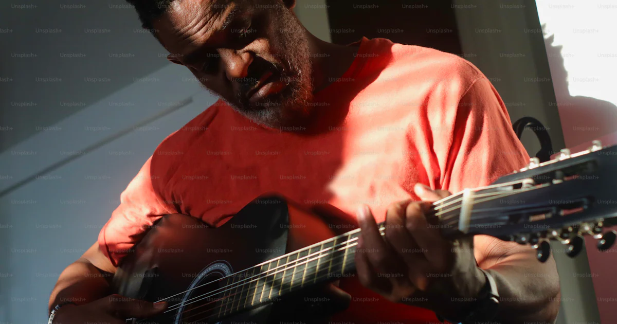 A man with dreadlocks playing a guitar photo – Musical instrument Image ...