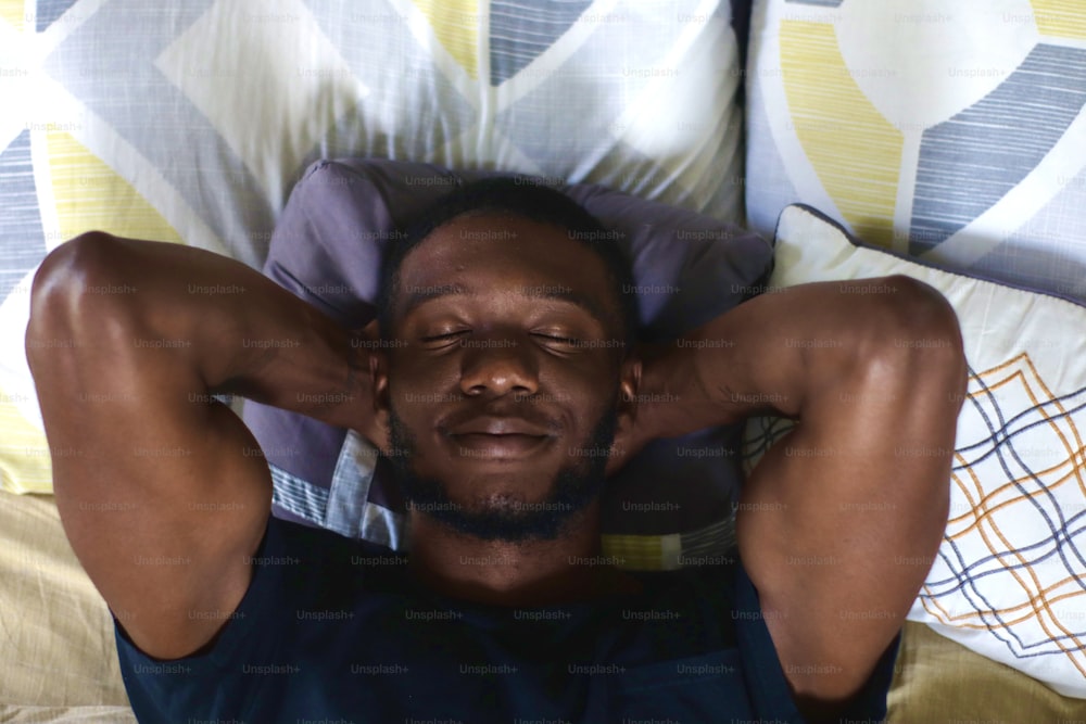 a man laying on a bed with his hands behind his head
