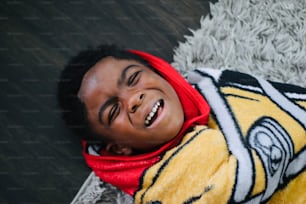 Um menino sorri deitado no chão
