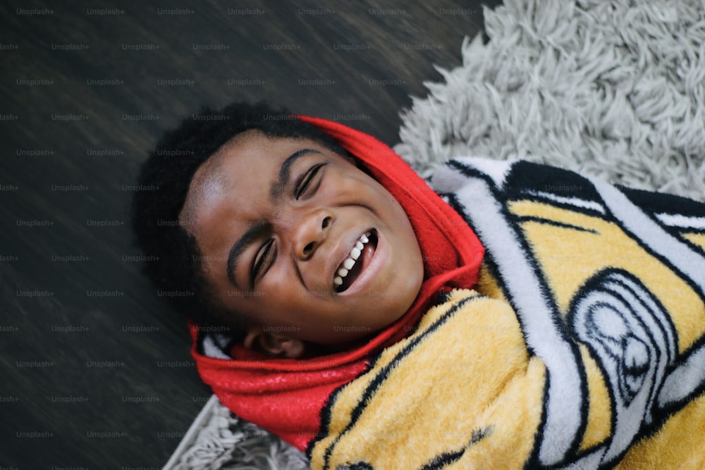 a young boy smiles while laying on the floor