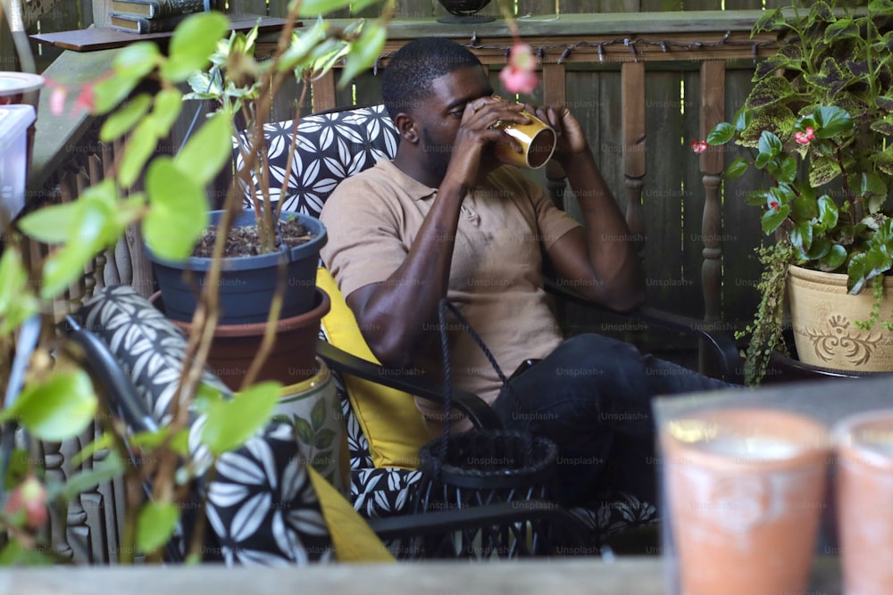 a man sitting in a chair drinking from a cup