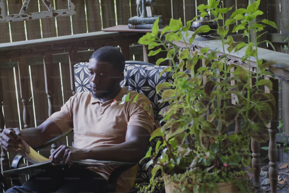 a man sitting in a chair with a plant in front of him