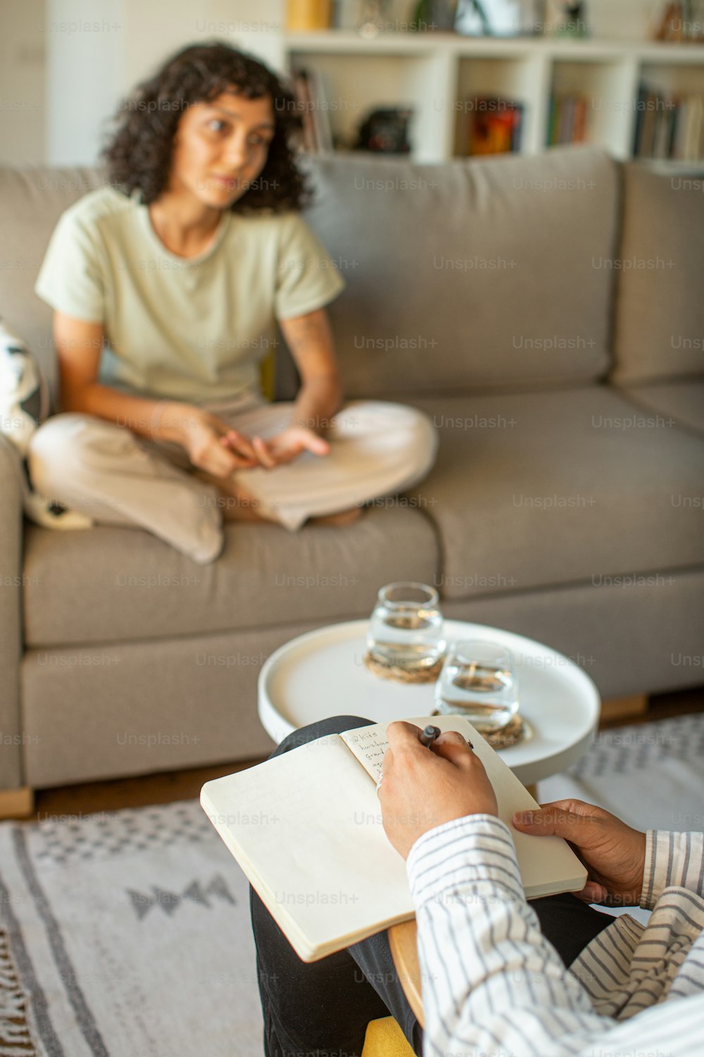uma mulher sentada em um sofá escrevendo em um caderno