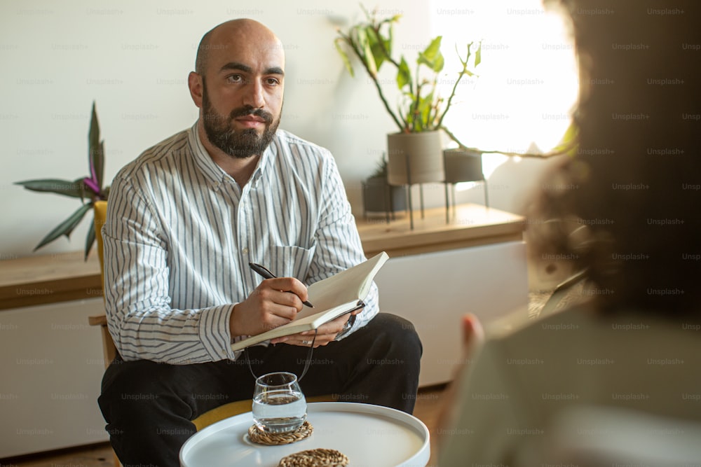 a man sitting at a table writing on a piece of paper