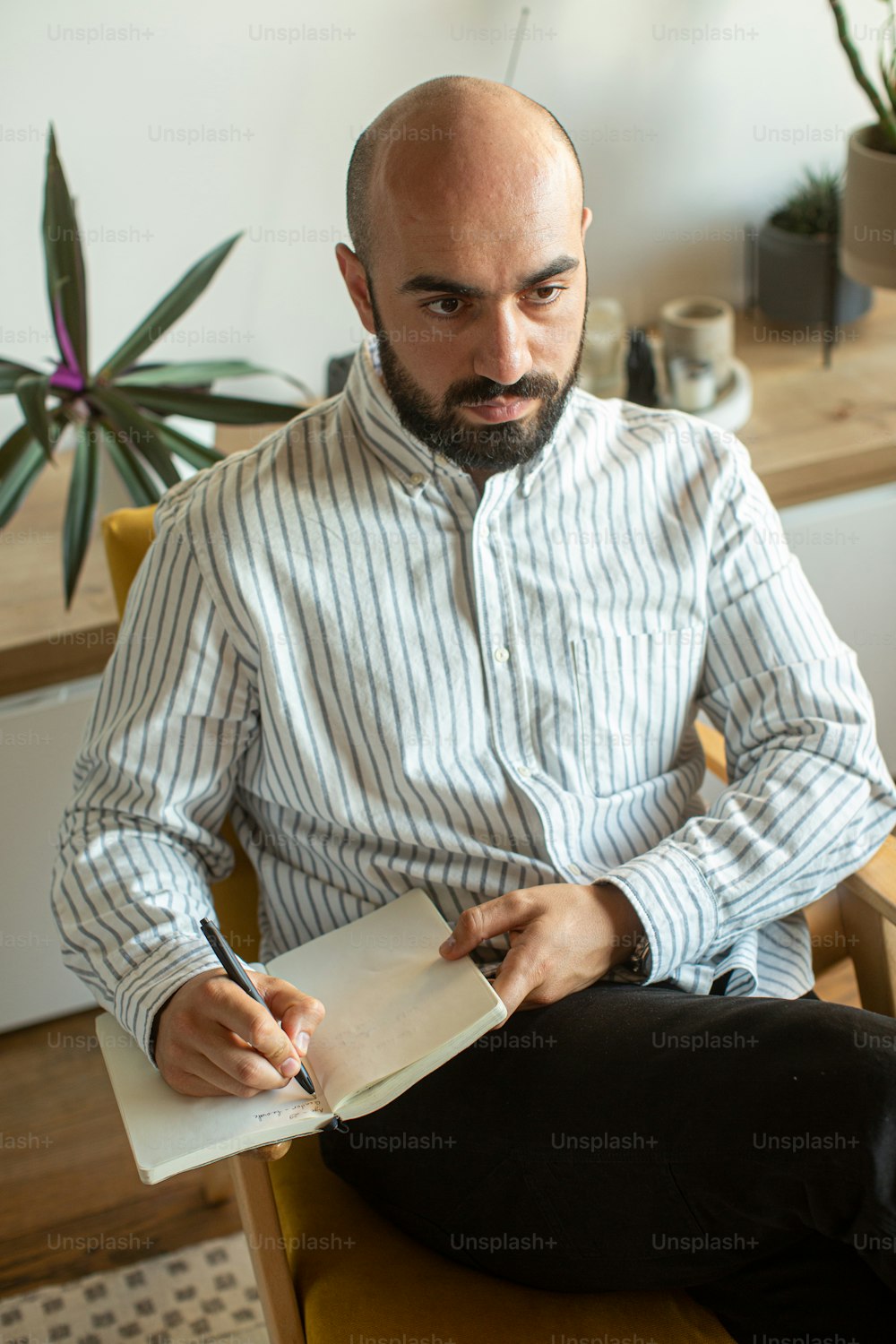 um homem sentado em uma cadeira escrevendo em um pedaço de papel