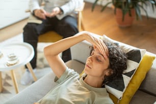 Eine Frau, die mit der Hand auf dem Kopf auf einer Couch sitzt