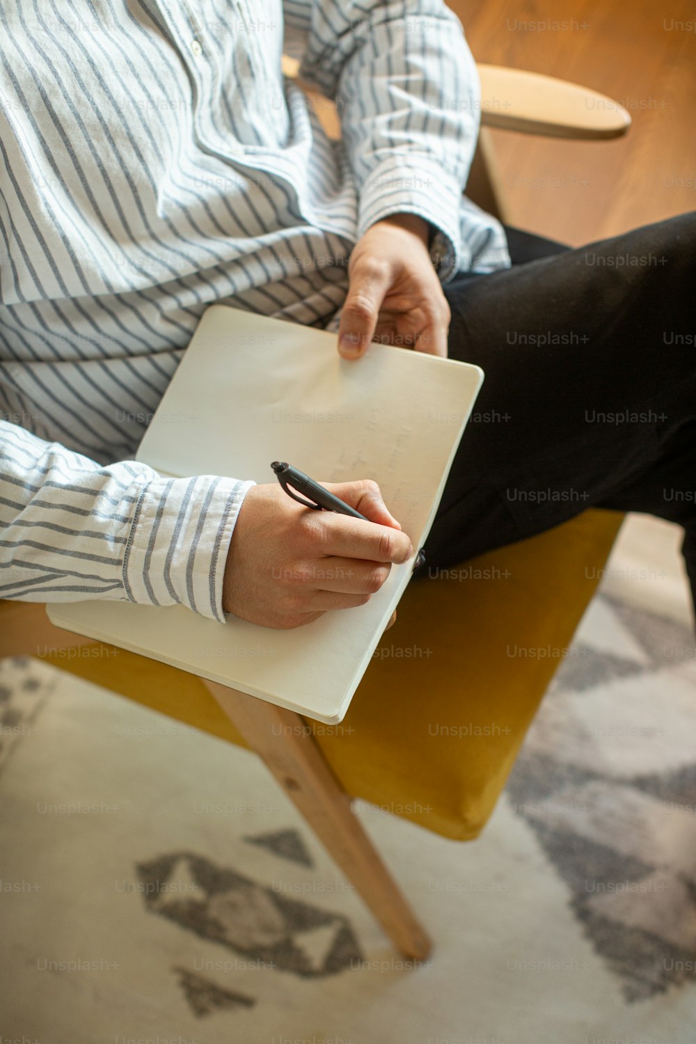 um homem sentado em uma cadeira escrevendo em um pedaço de papel