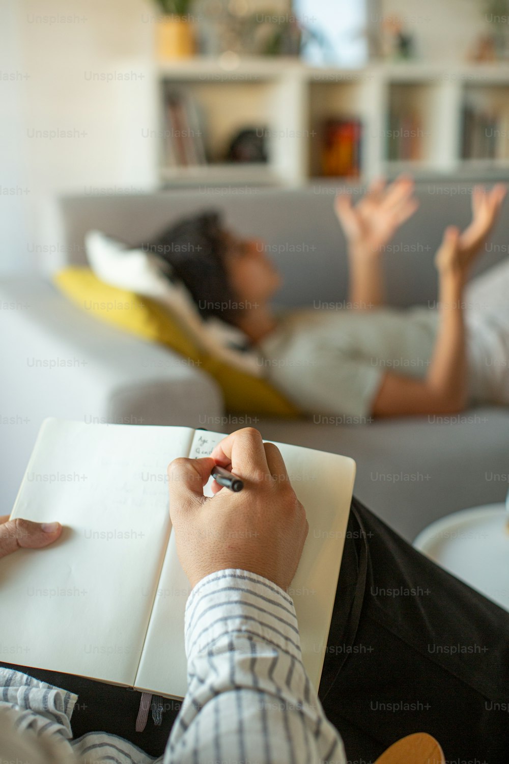 a person sitting on a couch writing on a notebook