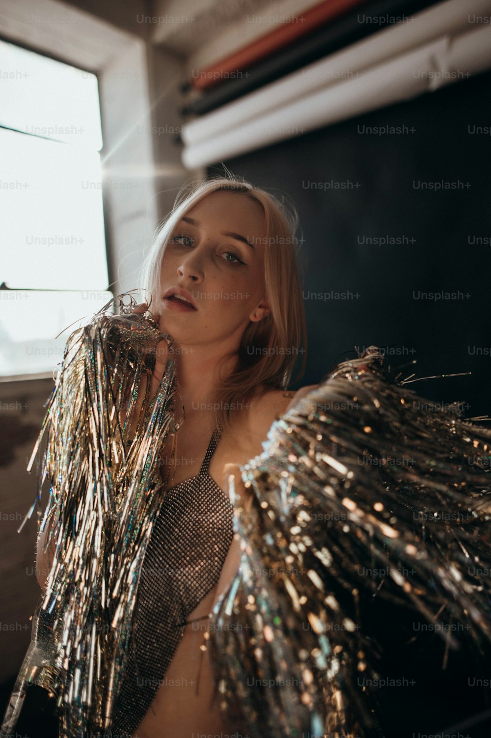 a woman in a silver dress holding a bunch of tinsel