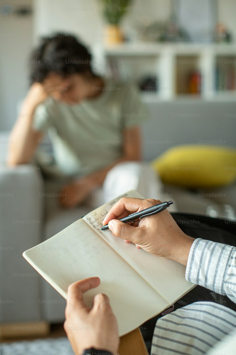 a woman sitting on a couch holding a pen and paper