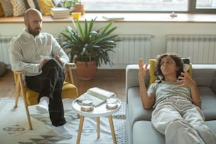 a man sitting in a chair next to a woman on a couch