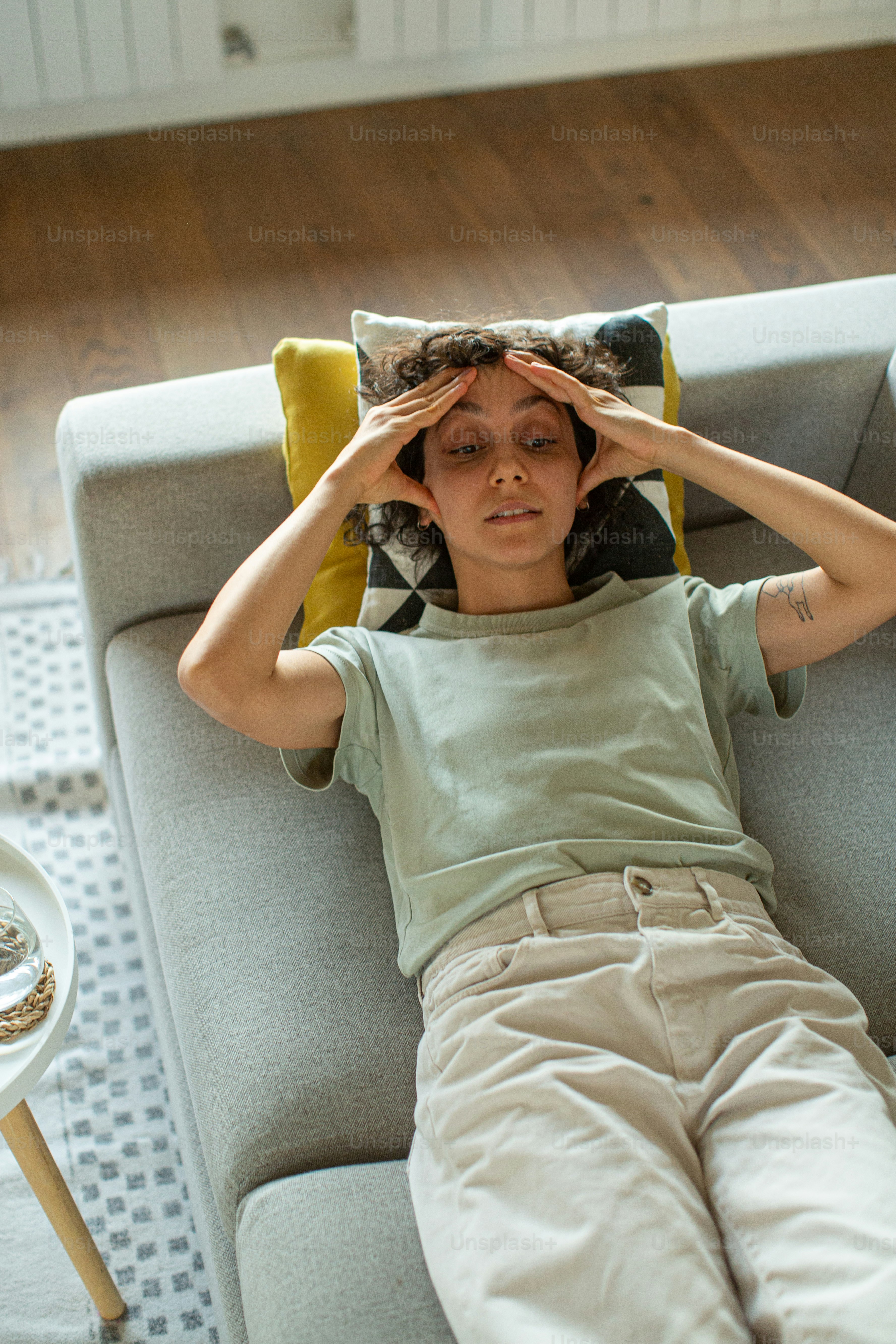 a woman sitting on a couch with her hands on her head
