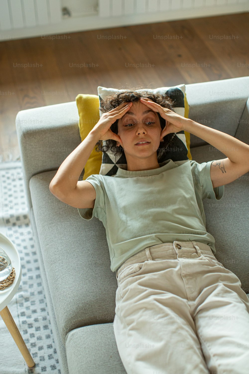 Una donna seduta su un divano con le mani sulla testa