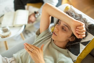 a woman sitting on a couch with her hand on her head