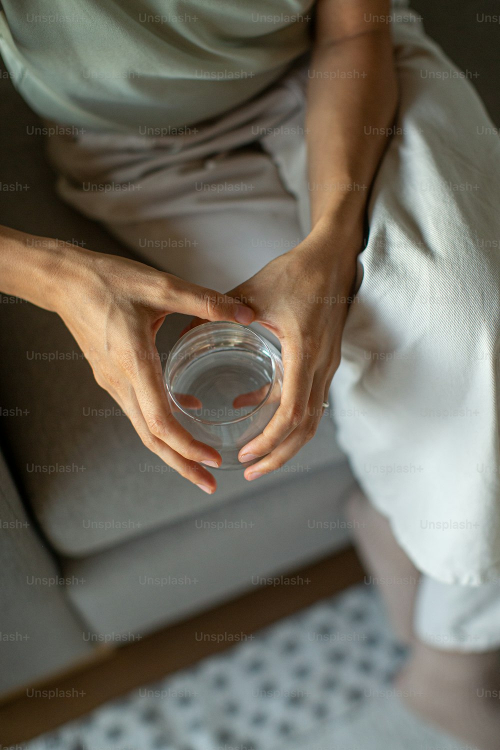 una persona seduta su un divano che tiene una tazza