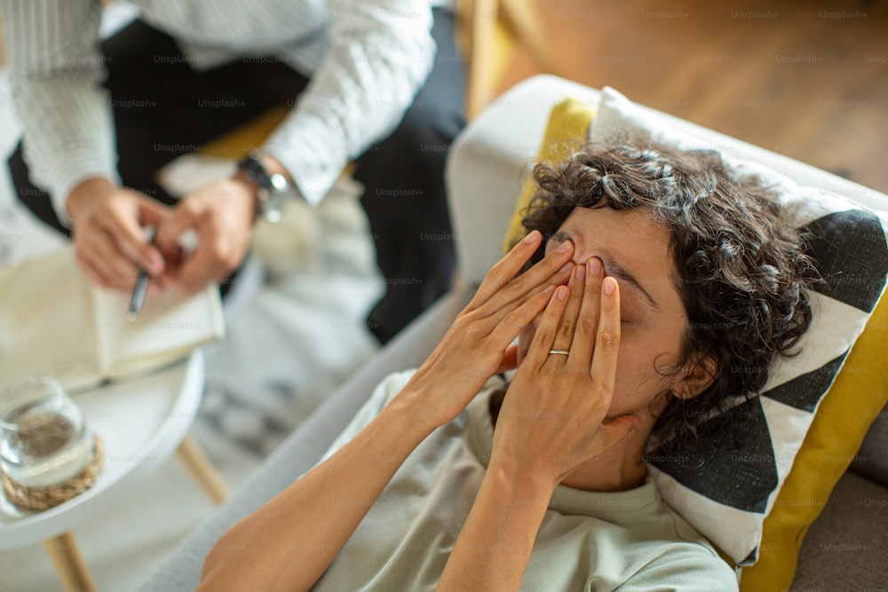 una donna sdraiata su un divano che copre i suoi occhi