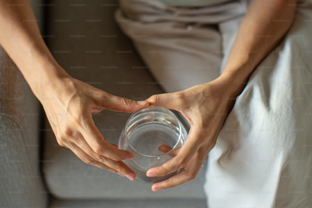 a person sitting on a couch holding a glass of water