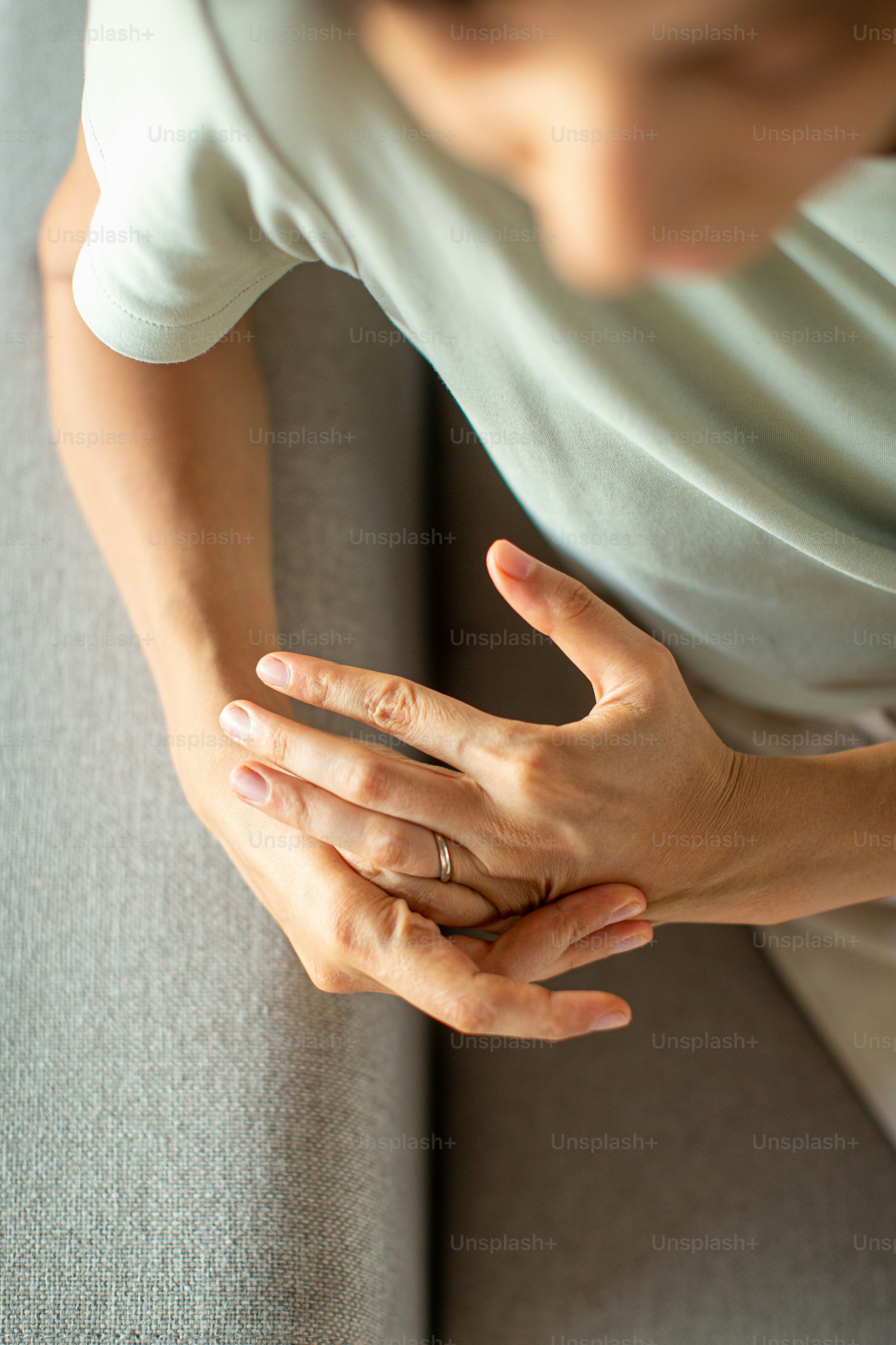a person sitting on a couch holding their hands together