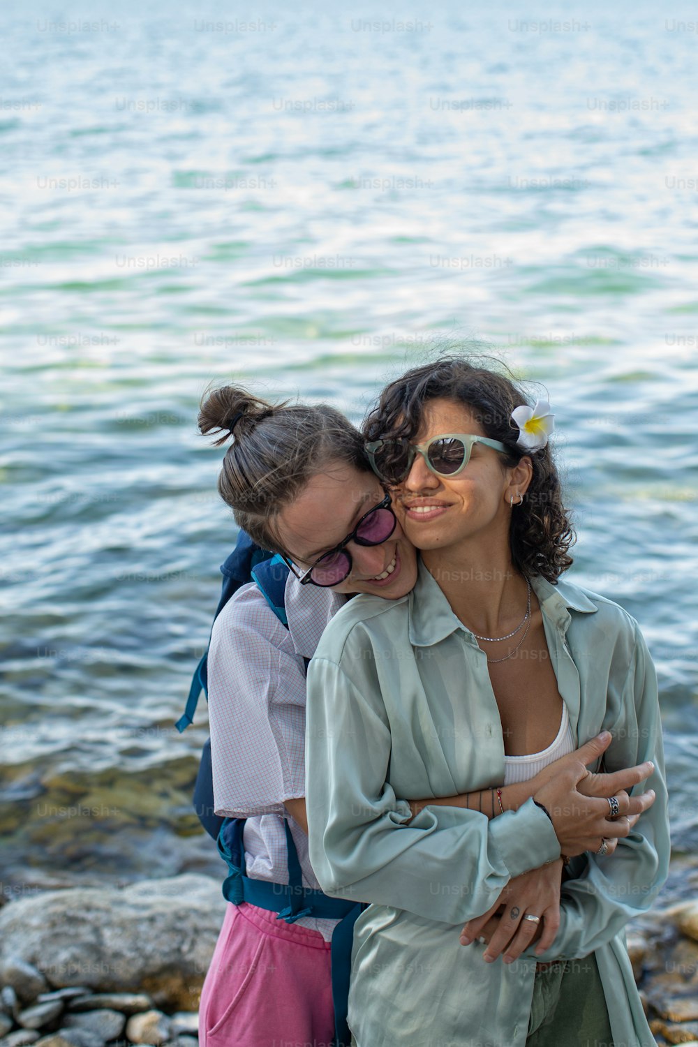 two women hugging each other by the water