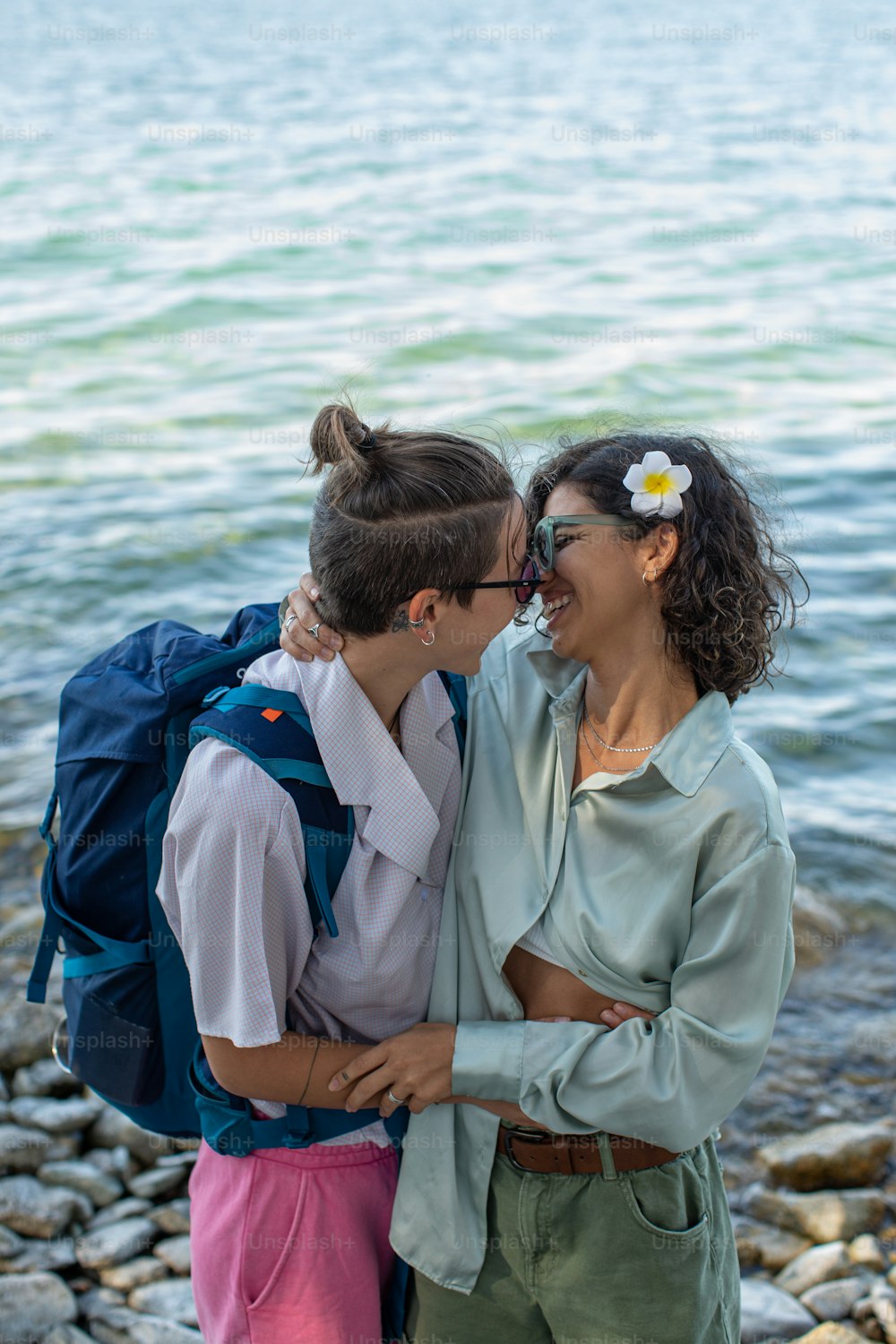 two women standing next to each other near a body of water