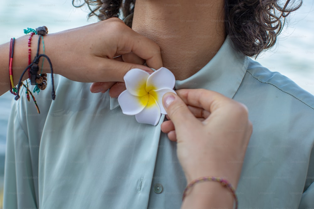 a woman is putting a flower on another woman's shirt