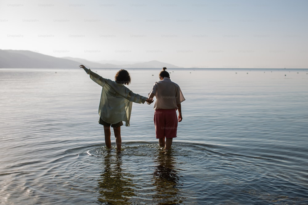two women standing in the water holding hands