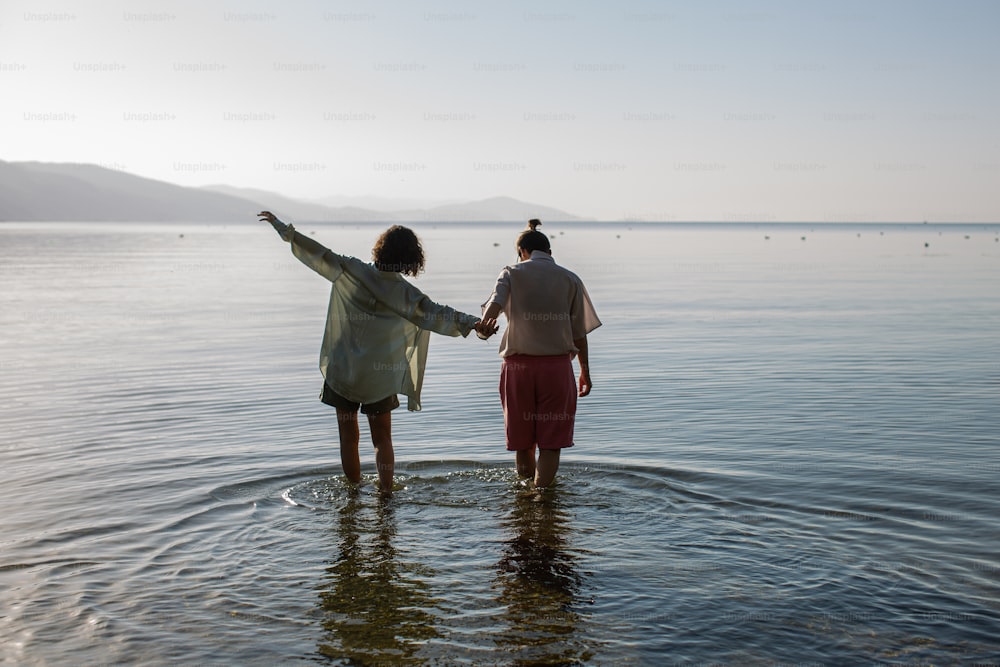 Dos mujeres de pie en el agua tomadas de la mano