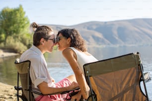 a man and a woman kissing while sitting on a beach chair