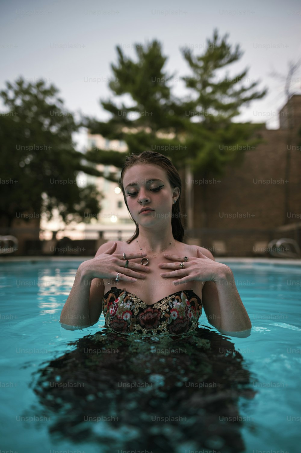 a woman sitting in a pool with her hands on her chest