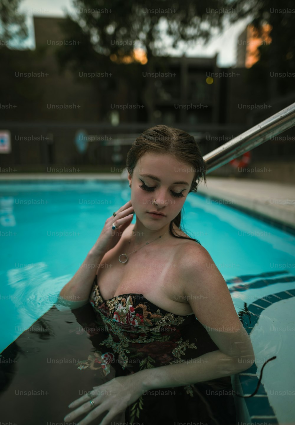Una mujer parada en una piscina hablando por teléfono celular