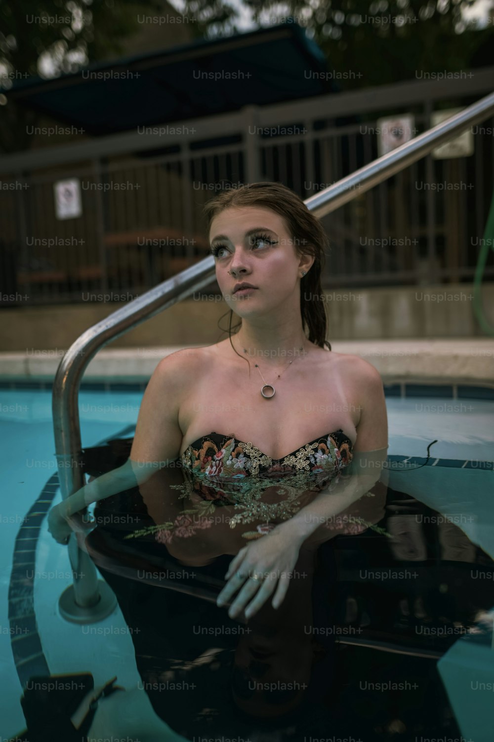 Una mujer sentada en una piscina con la mano en el borde de la piscina