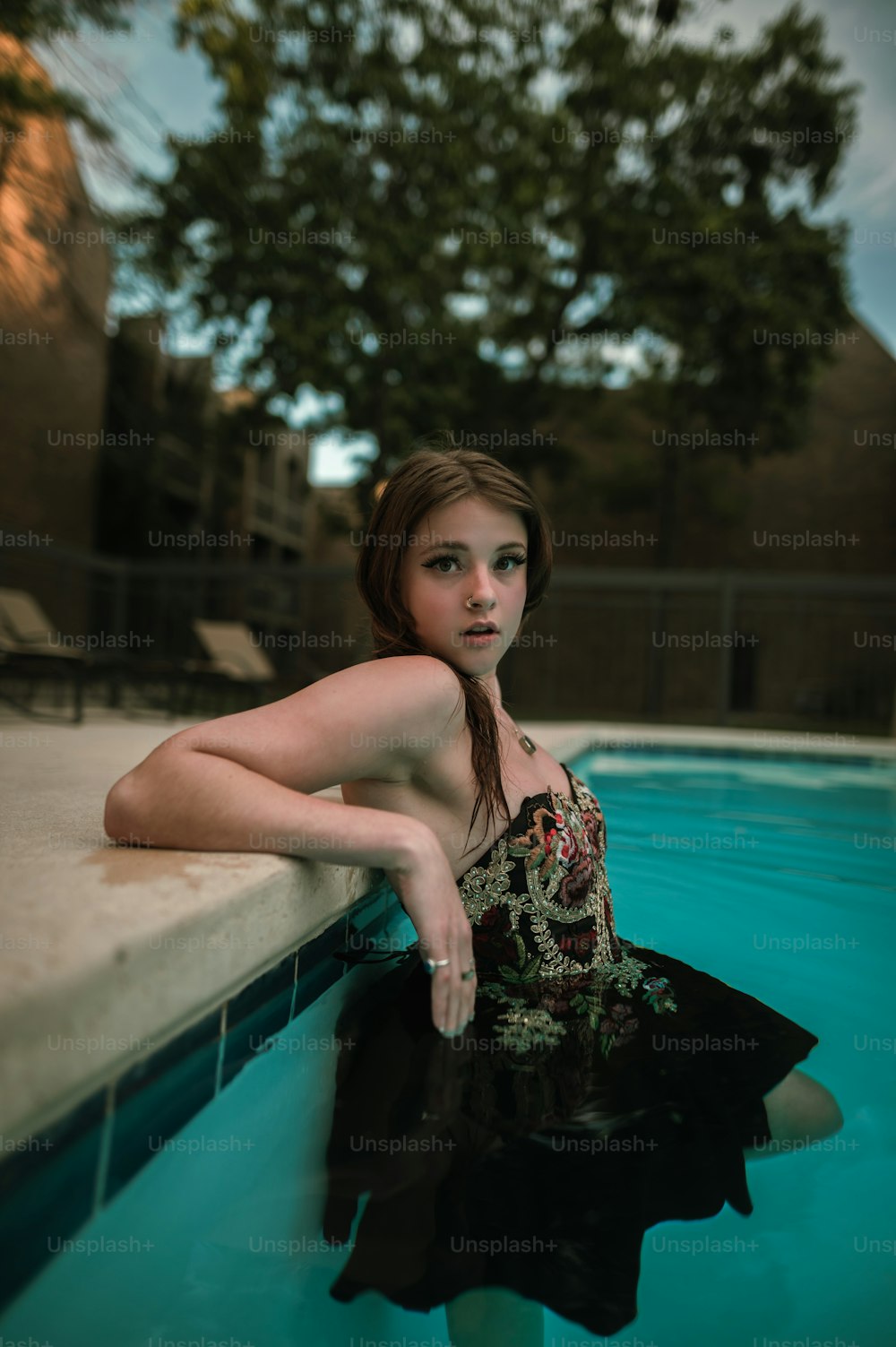 uma mulher em um vestido preto sentado em uma piscina