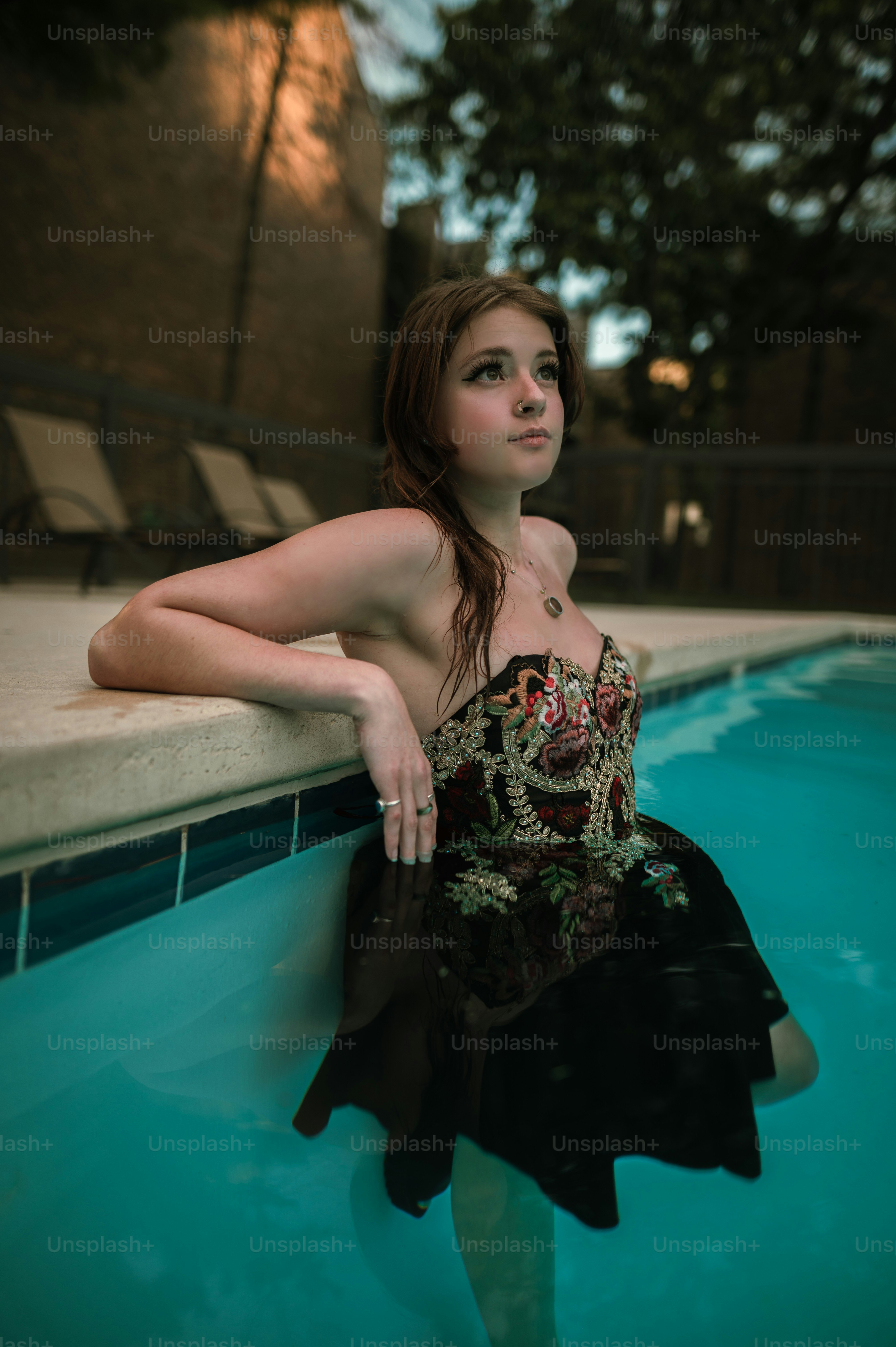 Eine Frau in einem schwarzen Kleid sitzt in einem Pool