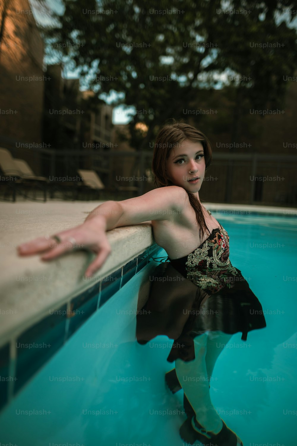 a woman leaning against a wall next to a swimming pool