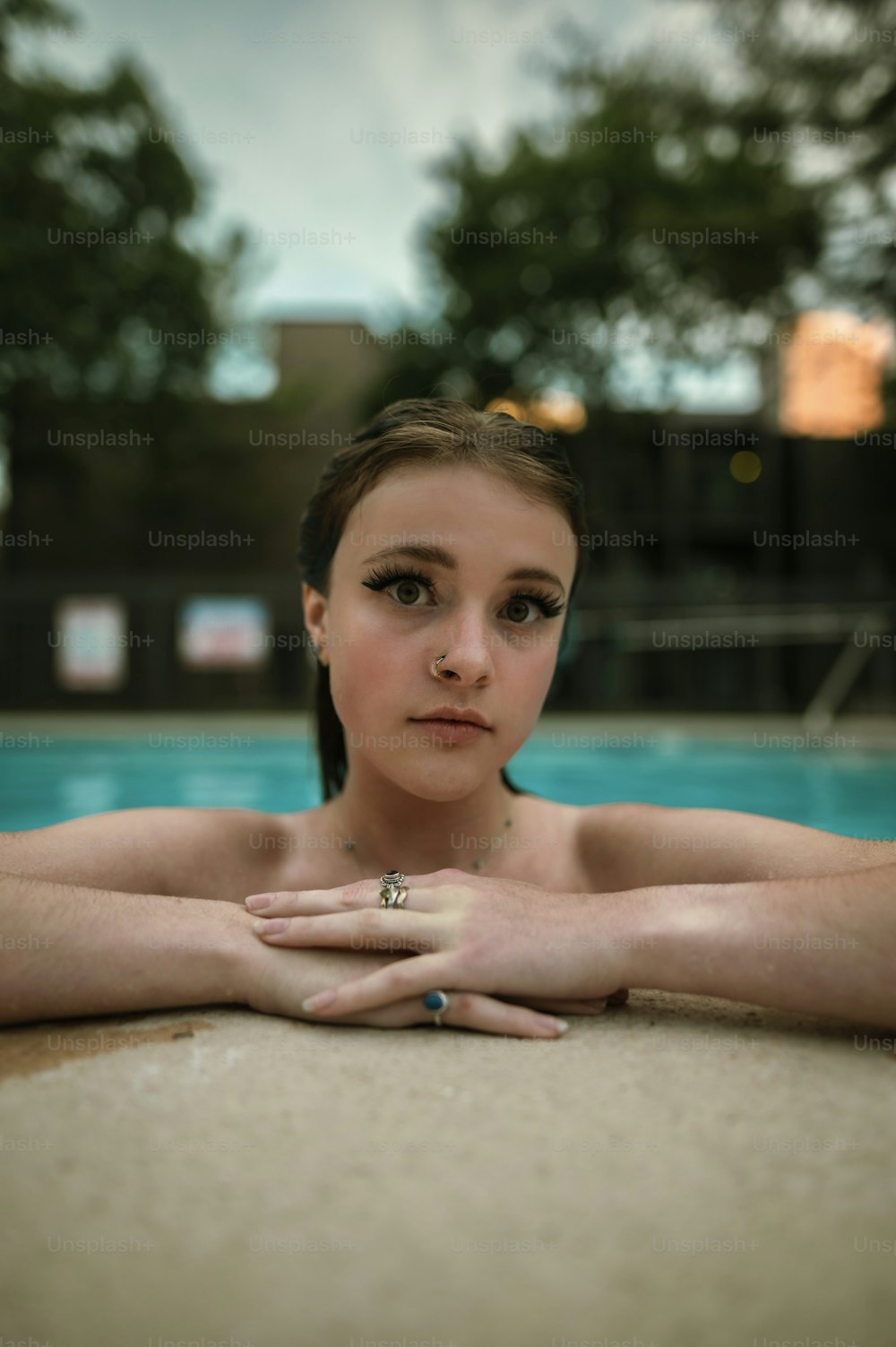 a young woman sitting in front of a swimming pool
