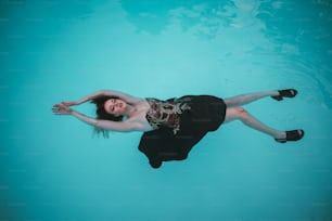 a woman in a black dress floating in a pool
