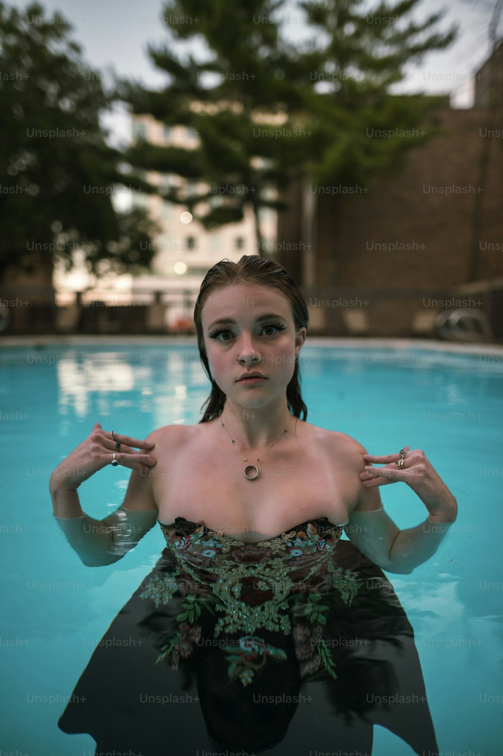 uma mulher em um vestido preto em pé em uma piscina