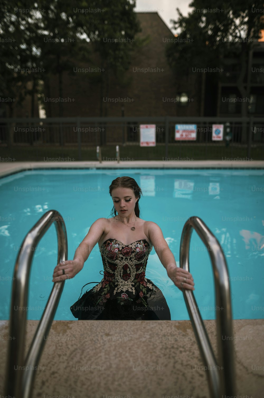 a woman in a corset sitting in front of a swimming pool